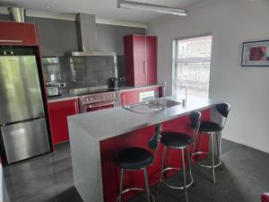 a kitchen with red cabinets and a counter with bar stools at De Vine Martinborough #14a in Martinborough +7 photos