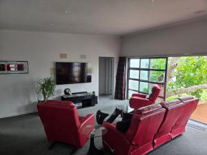 a woman sitting in a living room with two red chairs at De Vine Martinborough #14a in Martinborough