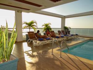two people sitting on lounge chairs next to a swimming pool at Hotel Summer Frente Al Mar in Cartagena de Indias