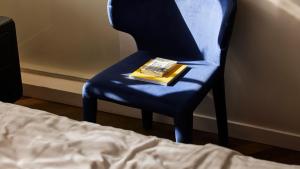 a book sitting on a blue chair next to a bed at Jacob Shenkin Hotel in Tel Aviv