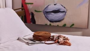 a basket and magazines on a bed with a painting at Jacob Shenkin Hotel in Tel Aviv +69 photos