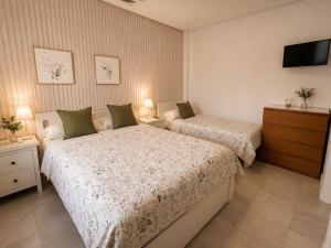 a bedroom with two beds and a flat screen tv at Hostal Baobab in El Puerto de Santa María
