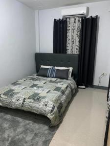 a bedroom with a bed with a green headboard and curtains at maica's apartment in Taytay