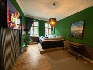 a bedroom with green walls and a bed and a desk at Danmarksgade Green Suites in Aalborg