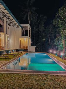 a swimming pool in front of a house at night at Nilwadula Hotel Udawalawe in Ratkarawwa