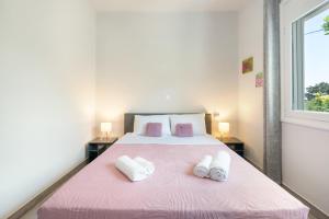 a bedroom with a pink bed with two towels on it at 30Roses House in Sálakos +22 photos