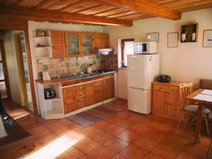 a kitchen with a white refrigerator and wooden cabinets at Zelená chalúpka a Zelený domček in Hrabušice