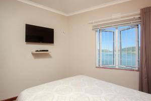 a bedroom with a bed with a television and a window at Ilse's Garden Route Gem in Knysna