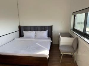 a small bedroom with a bed and a chair at Homestay Lê Thảo in Ấp Ða Lợi