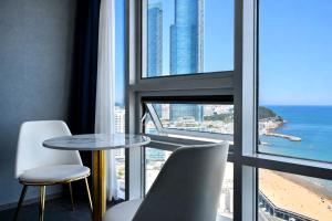 a table and chairs in a room with a view of the ocean at Sun Cloud Hotel in Busan