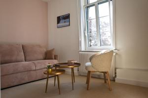 a living room with a couch and a table and a chair at Le Presbytère in Ambleteuse