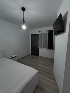 a bedroom with a white bed and a flat screen tv at Casa Mihai in Costinesti