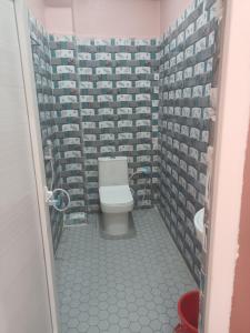a bathroom with a toilet and a tile wall at HOTEL अtithi in Rājgīr
