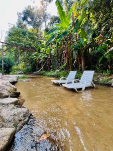 two white chairs sitting in the water in a river at วิวดี ป่าเหมี้ยง โฮมสเตย์ in Ban Pa Miang