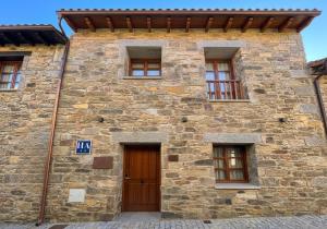a stone building with a wooden door and windows at Hotel Apartamento 3 Lobitos in Villardeciervos