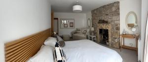 a bedroom with a bed and a stone fireplace at Balmungo Cottage B&B in St. Andrews