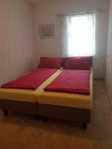 Schlafzimmer mit einem Bett mit roter Bettwäsche und einem Fenster in der Unterkunft Fino da Mario in Ebersbach an der Fils