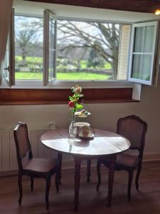 a table with two chairs and a vase with flowers on it at "C'est Si Bon" in Vandenesse