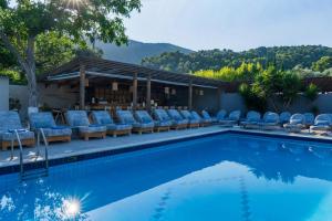 a swimming pool with lounge chairs and a bar at Skiathos Thalassa, Philian Hotels and Resorts in Skiathos