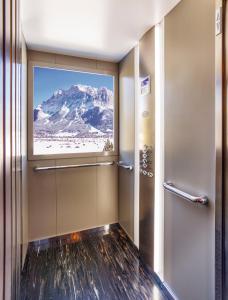 a bathroom with a window with a mountain view at Sporthotel Pechtl in Lermoos