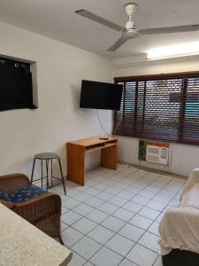 a room with a flat screen tv and a desk at Pacific Cay motel in Cairns North