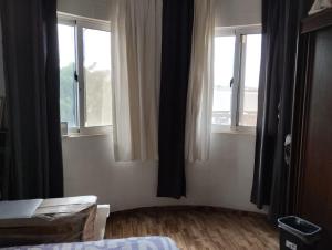 a room with two windows and a bed in it at Comfortable 2-Bedroom Apartment, Monte Sossego in Mindelo