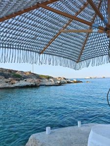 a view of the ocean from under a straw umbrella at Troulou beach house in Kimolos