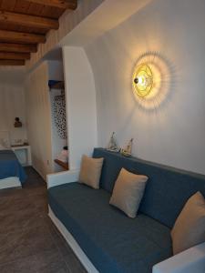 a living room with a blue couch with a light on the wall at Troulou beach house in Kimolos