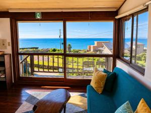 a living room with a blue couch and a view of the ocean at Emeraldia in Tateyama