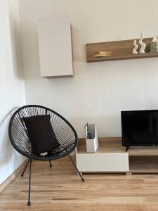 a black chair sitting in a living room with a tv at AeraSuites Komárom in Komárom +6 photos