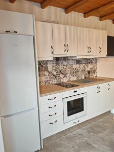 a kitchen with white cabinets and a white refrigerator at Troulou beach house in Kimolos +4 photos