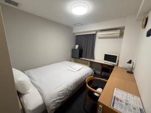 a room with a bed and a desk with a computer at アーバンホテル森下 in Tokyo