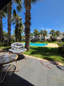 a chair and a table next to a pool at Villa Triplex avec piscine proche de la mer in El Harhoura