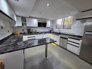 a large kitchen with white cabinets and a black counter top at Villa Triplex avec piscine proche de la mer in El Harhoura