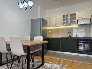 a kitchen with green cabinets and a wooden table and chairs at Olive Šušanj Apartment in Bar