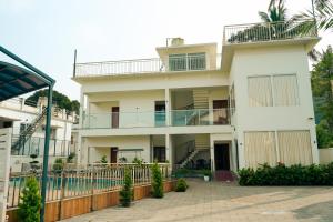 a large white house with a balcony at La Dimora luxury pool villa in Vythiri
