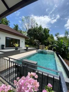 a swimming pool in the backyard of a house with pink flowers at The Villa at Mertolas in Alitagtag