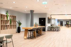 a lobby with a bar with stools and tables at Scandic Stavanger Forus in Stavanger