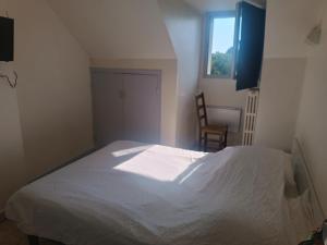 a bedroom with a white bed and a chair at Hôtel des Pyrénées in Laloubère