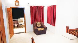 a chair sitting in a room with red curtains at Sri Ram Villa in Rāmeswaram