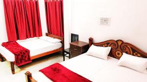 a bedroom with two beds and red curtains at Sri Ram Villa in Rāmeswaram
