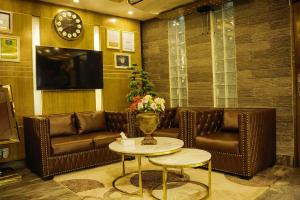 a living room with leather couches and a tv at Hotel Shuktara Dhaka in Dhaka