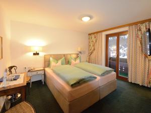 a bedroom with a bed and a desk and a window at Hotel-Garni Felsenhof in Lech am Arlberg