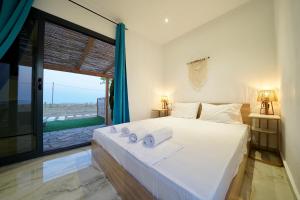 a bedroom with a large white bed and a large window at Almond Beachfront Resort - kalyves Halkidiki in Kalives Poligirou