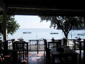 a view of a restaurant with tables and boats in the water at Galang Kangin Bungalows 2 in Amed