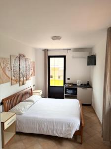 a bedroom with a white bed and a kitchen at Agriturismo Terra Del Mare in Fossalòn