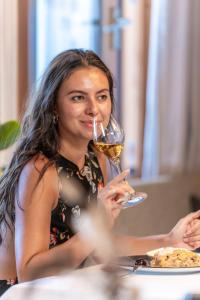 a woman sitting at a table drinking a glass of wine at Granpanorama Hotel StephansHof in Villandro +91 photos