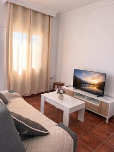 a living room with a tv and a couch and a table at Apartamentos Los Mellizos in Conil de la Frontera
