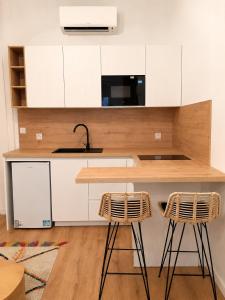 a kitchen with white cabinets and two bar stools at Rose Joséphine in Ajaccio +6 photos