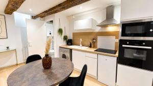 a kitchen with a table and a kitchen with white cabinets at L'Adresse Mâconnaise Central - 2pers - Calme in Mâcon